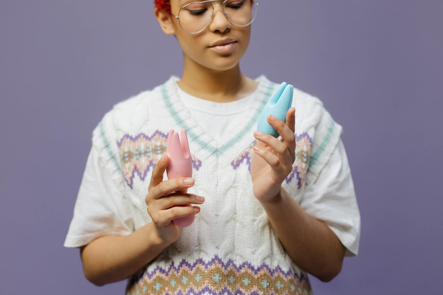 Woman holding colorful clitoral vibrators in contemplative pose