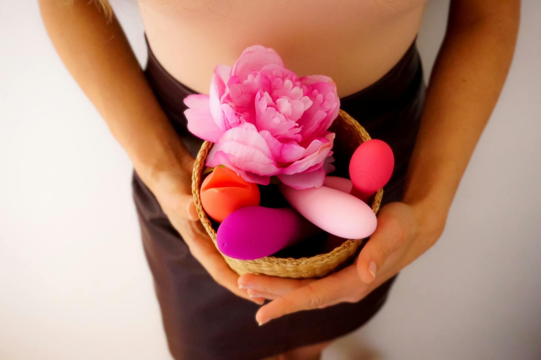 Colorful clitoral vibrators in a basket, representing diverse tools for pleasure and recovery